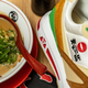 A ramen-inspired sneaker is next to a bowl of ramen.